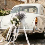 Balai de mariage attaché avec des rubans de satin blanc sur le pare-chocs d'une voiture de mariage sans abîmer la carrosserie