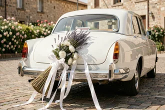 Balai de mariage attaché avec des rubans de satin blanc sur le pare-chocs d'une voiture de mariage sans abîmer la carrosserie