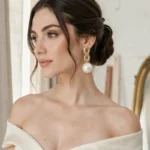 Mariée moderne portant une grande boucle d'oreille statement en perle et or, gros plan portrait élégant en atelier parisien