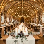 Salle de mariage d'hiver décorée de guirlandes lumineuses, bougies et branches de bouleau pour une ambiance féerique