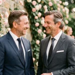 Deux hommes élégants souriants lors d'une réception de mariage en jardin, illustrant les rumeurs autour du mariage de Stéphane Marie