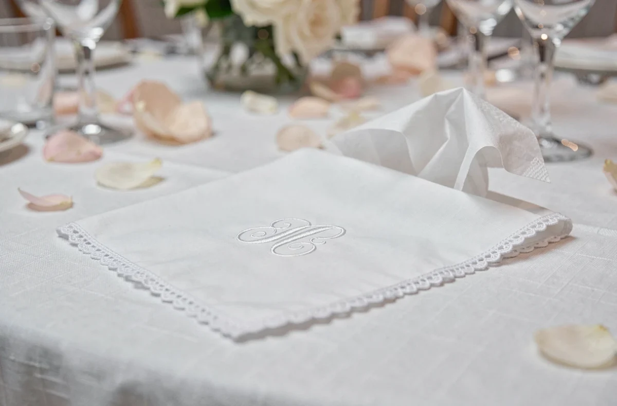 Mouchoir en tissu brodé et mouchoir en papier posés sur une nappe de table de mariage