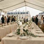 Grande réception de mariage parisienne avec tables dressées sous une marquise blanche, vaisselle raffinée et vue sur les toits haussmanniens
